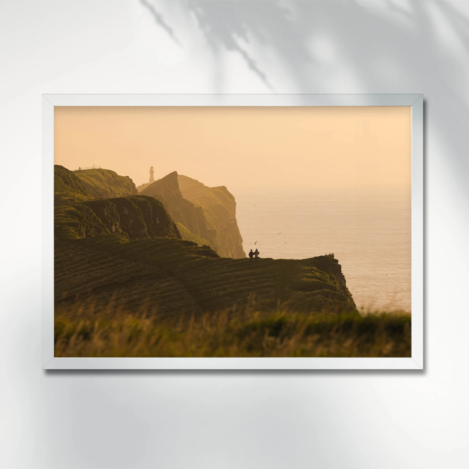 Couple overlooking sunset by cliffs in Mykines. Faroe Islands